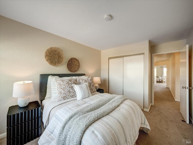 bedroom with a closet, light colored carpet, and baseboards