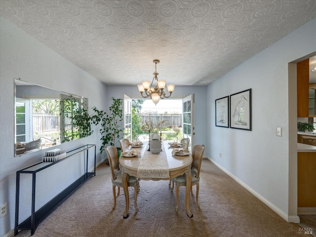 carpeted dining space with baseboards, an inviting chandelier, and a textured ceiling