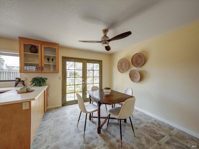 dining space with baseboards, a textured wall, french doors, a textured ceiling, and ceiling fan