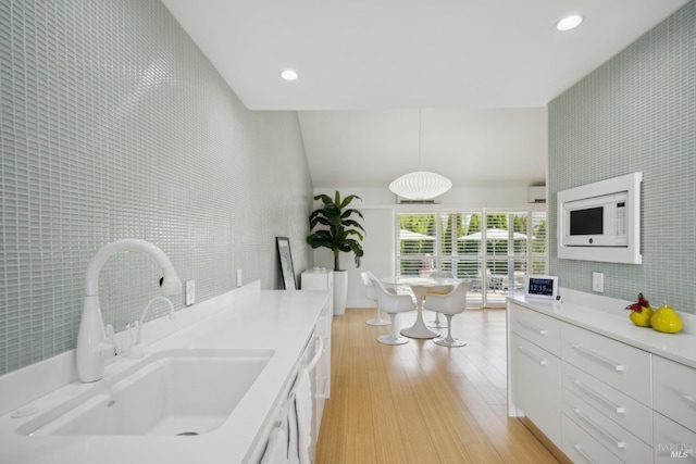 kitchen featuring a sink, light countertops, white cabinetry, recessed lighting, and light wood-style flooring
