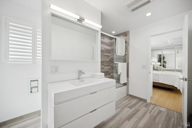 ensuite bathroom with vanity, recessed lighting, ensuite bathroom, visible vents, and wood finished floors