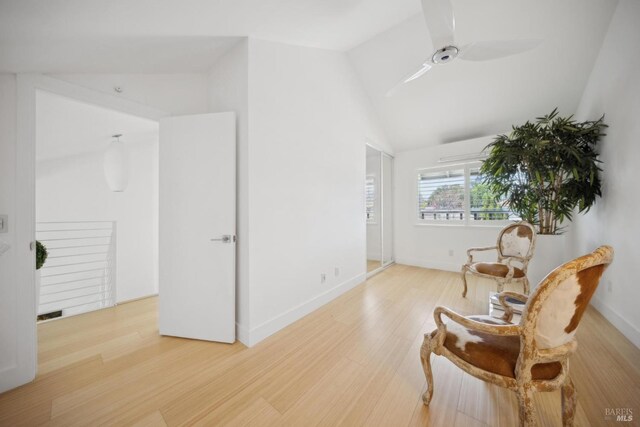 sitting room with baseboards, light wood-style flooring, vaulted ceiling, and a ceiling fan