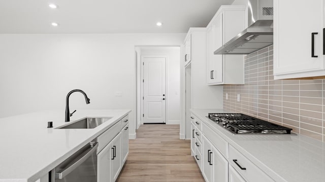 kitchen featuring a sink, appliances with stainless steel finishes, recessed lighting, and wall chimney exhaust hood