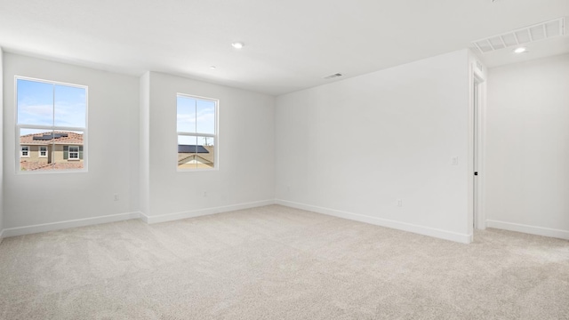 empty room with visible vents, recessed lighting, baseboards, and light colored carpet