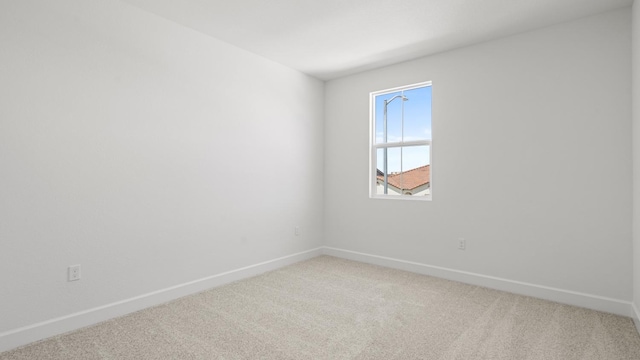 unfurnished room featuring baseboards and light carpet