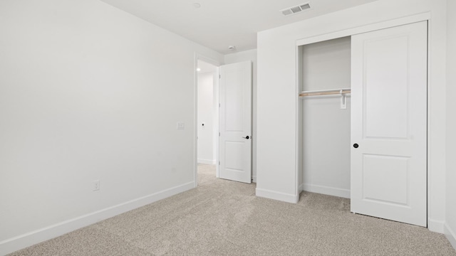 unfurnished bedroom with a closet, baseboards, light colored carpet, and visible vents