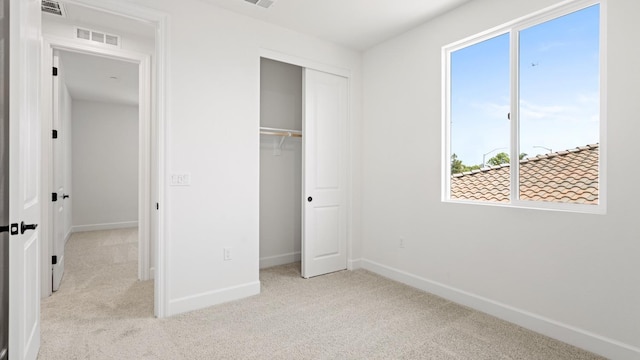 unfurnished bedroom with baseboards, multiple windows, carpet, and visible vents