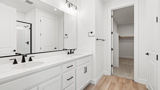 full bath with visible vents, a sink, double vanity, and a shower stall