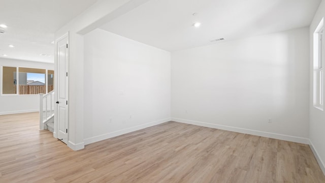 spare room featuring baseboards, visible vents, and light wood-style floors