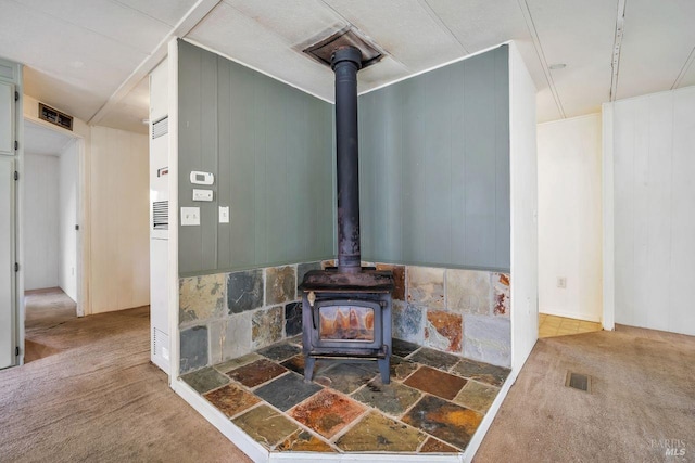 interior details featuring carpet floors, a wood stove, and visible vents