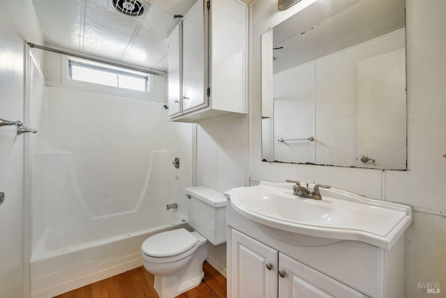 full bath with toilet, visible vents, wood finished floors, washtub / shower combination, and vanity