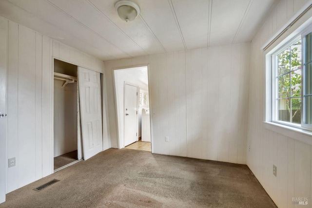 unfurnished bedroom featuring carpet floors, washer / clothes dryer, visible vents, and a closet