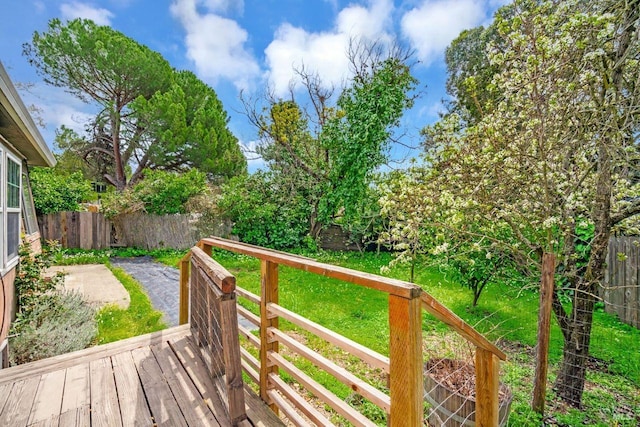 wooden terrace featuring fence and a yard