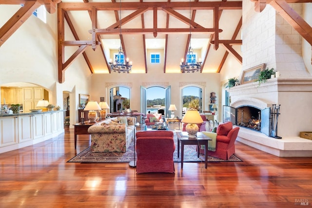 living room featuring a fireplace, an inviting chandelier, beam ceiling, and wood finished floors