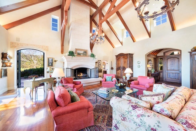 living room featuring visible vents, arched walkways, an inviting chandelier, beam ceiling, and wood finished floors