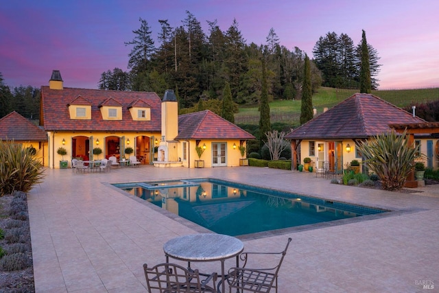pool featuring an outbuilding, a patio area, an exterior structure, and an in ground hot tub