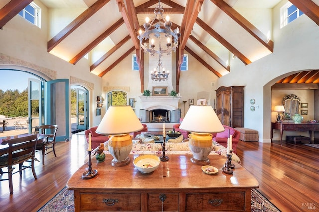 living room with high vaulted ceiling, arched walkways, wood finished floors, a notable chandelier, and beam ceiling