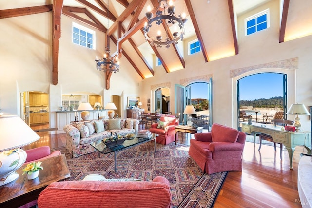 living room featuring wood finished floors, beamed ceiling, a notable chandelier, and high vaulted ceiling