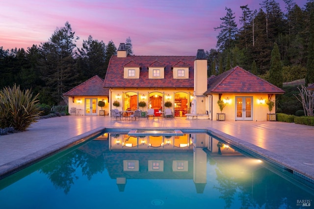outdoor pool featuring a hot tub, a storage structure, an outdoor structure, a patio area, and french doors