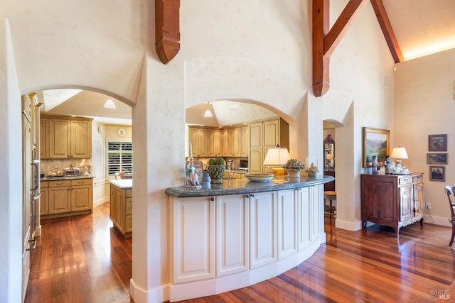 kitchen featuring arched walkways, tasteful backsplash, baseboards, and wood finished floors