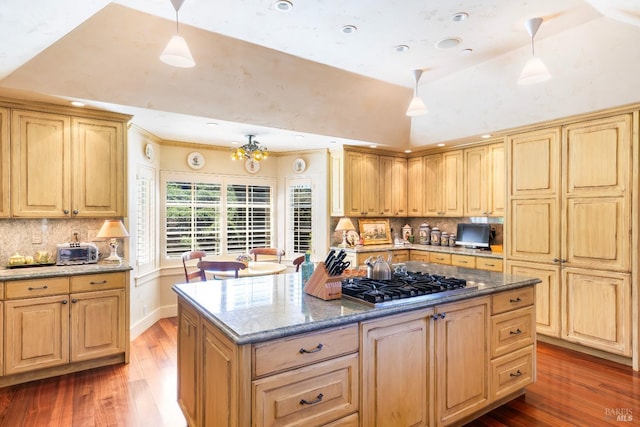 kitchen featuring a kitchen island, stainless steel gas stovetop, backsplash, and wood finished floors