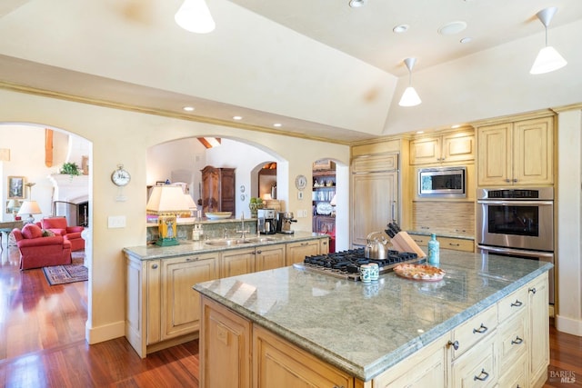 kitchen featuring built in appliances, light stone countertops, arched walkways, a sink, and wood finished floors