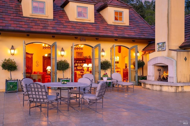 view of patio / terrace with outdoor dining area and a warm lit fireplace