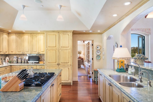 kitchen with dark wood-style flooring, backsplash, arched walkways, stainless steel gas stovetop, and a sink