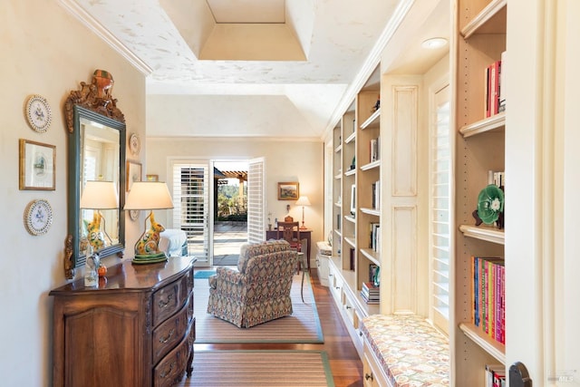 sitting room with a raised ceiling, crown molding, and wood finished floors