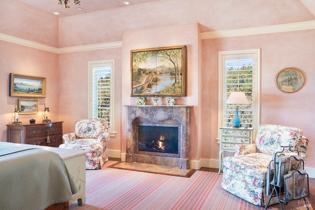 bedroom featuring a high end fireplace, ornamental molding, and baseboards