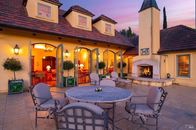 view of patio / terrace featuring a lit fireplace and outdoor dining space