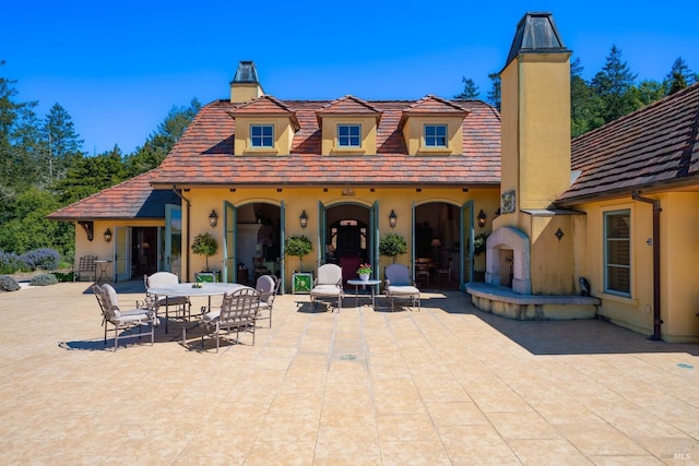 rear view of property with a patio area, stucco siding, and a chimney