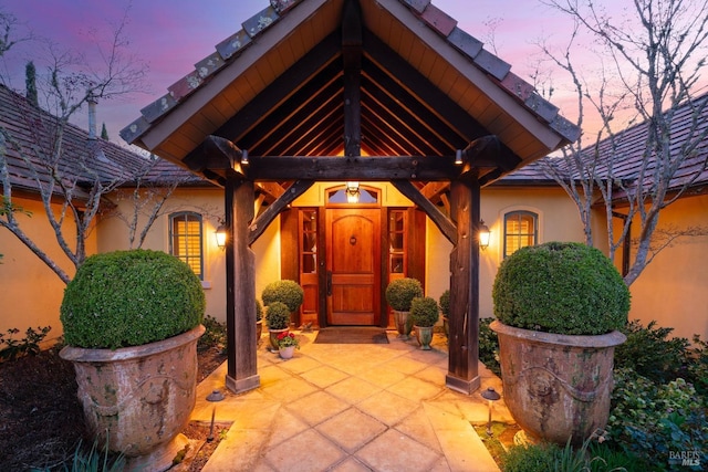 exterior entry at dusk featuring stucco siding