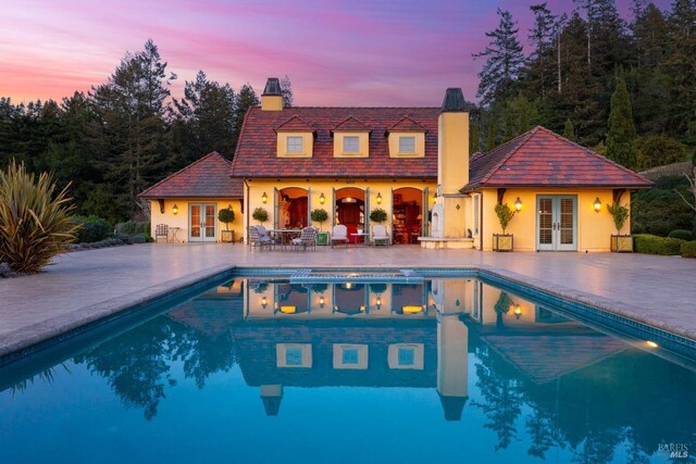 outdoor pool with a storage structure, french doors, a patio area, and an outdoor structure