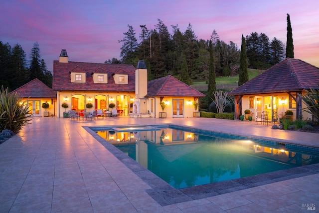outdoor pool with a jacuzzi, a patio, a storage structure, and an outdoor structure