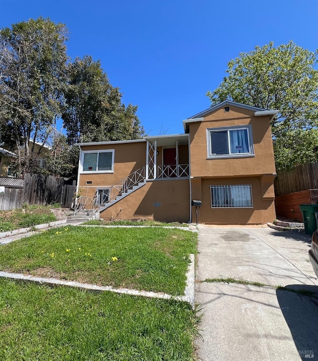 view of front facade with fence, a front lawn, and stucco siding