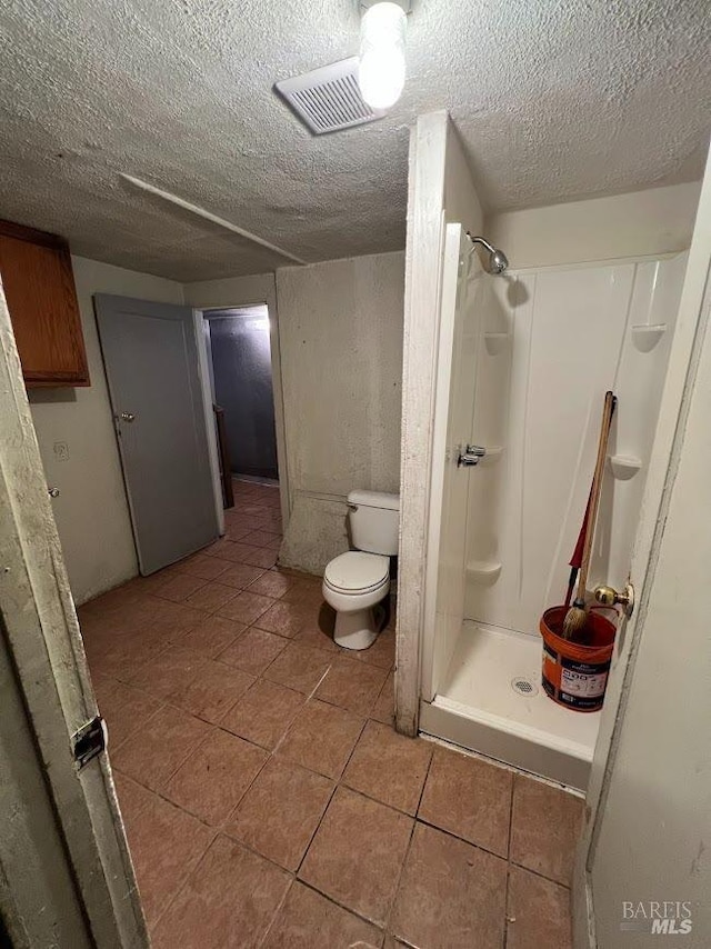 full bath featuring a textured ceiling, visible vents, a shower stall, tile patterned floors, and toilet