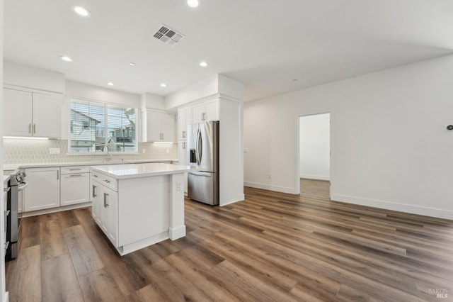 kitchen with stainless steel fridge with ice dispenser, visible vents, white cabinetry, stove, and decorative backsplash