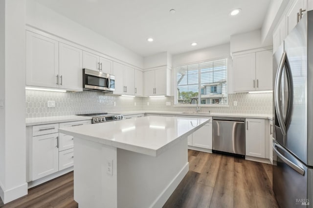 kitchen with white cabinetry, appliances with stainless steel finishes, light countertops, a sink, and dark wood-style floors
