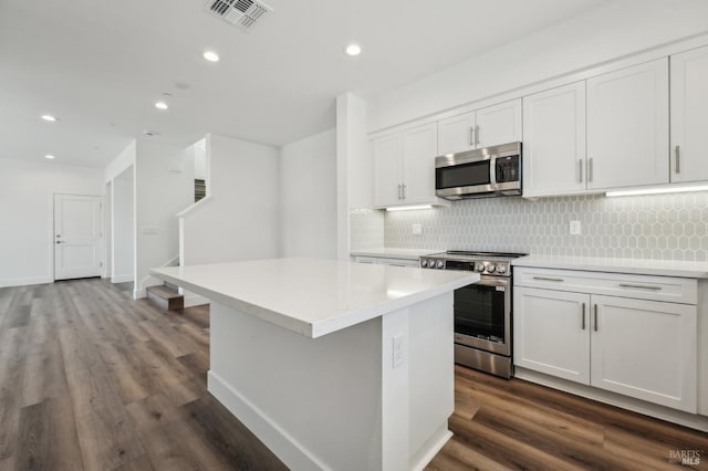 kitchen with dark wood finished floors, tasteful backsplash, visible vents, appliances with stainless steel finishes, and light countertops
