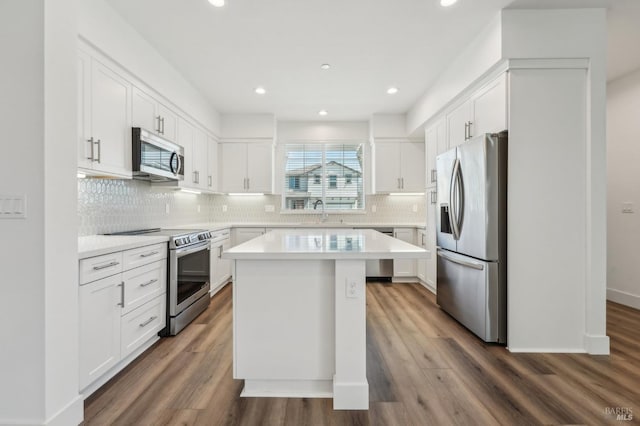 kitchen with dark wood-style flooring, a center island, light countertops, white cabinets, and appliances with stainless steel finishes