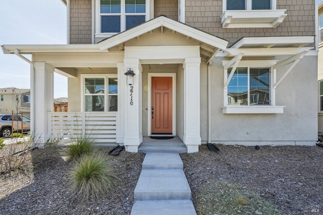 view of exterior entry featuring covered porch and stucco siding