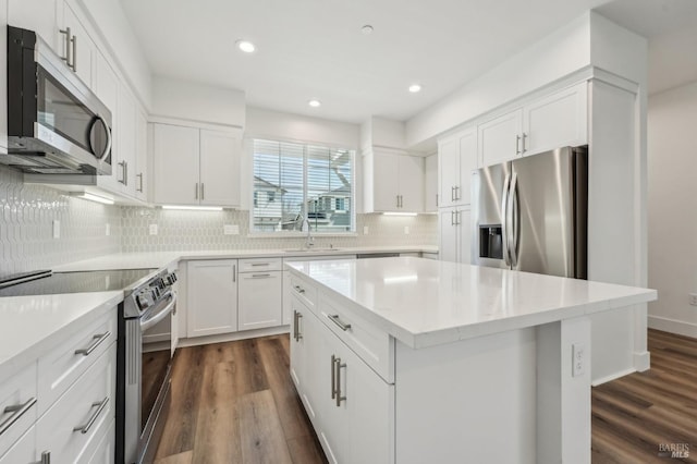 kitchen featuring a sink, backsplash, appliances with stainless steel finishes, and dark wood-type flooring