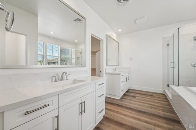 full bathroom featuring a shower stall, wood finished floors, a sink, and visible vents
