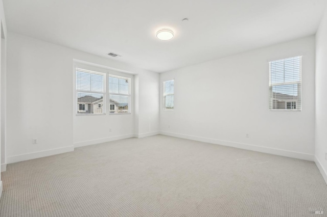 empty room featuring light carpet, baseboards, and visible vents