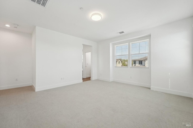 unfurnished room featuring light colored carpet, baseboards, and visible vents