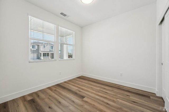 spare room featuring visible vents, baseboards, and wood finished floors