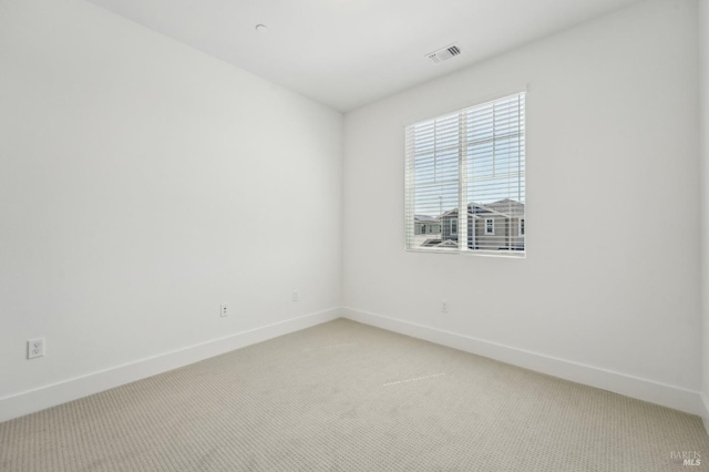 empty room featuring light colored carpet, baseboards, and visible vents