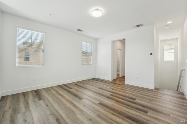 spare room with a wealth of natural light, visible vents, and wood finished floors