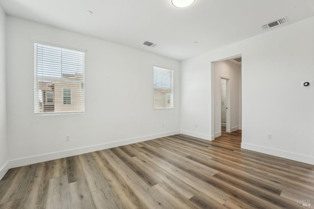 unfurnished room featuring visible vents, baseboards, and wood finished floors